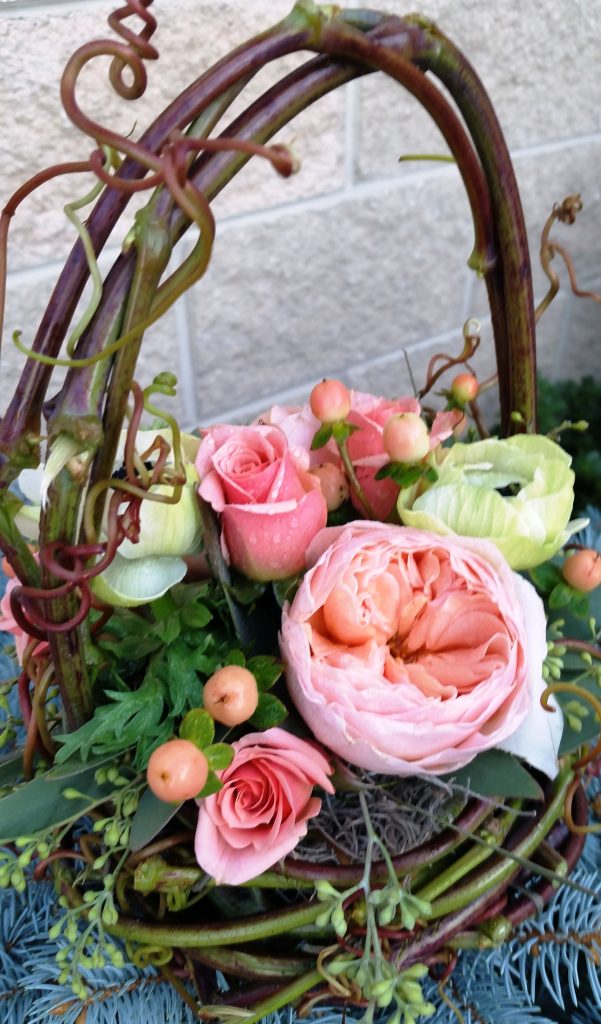 A sweet flower girl basket created with fresh grapevine and filled with roses and ranunculus.